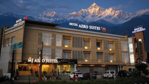 A hotel with multiple suites and a coffee shop, set against a backdrop of snow-capped mountains. - MJ AERO SUITE (Rishikesh)