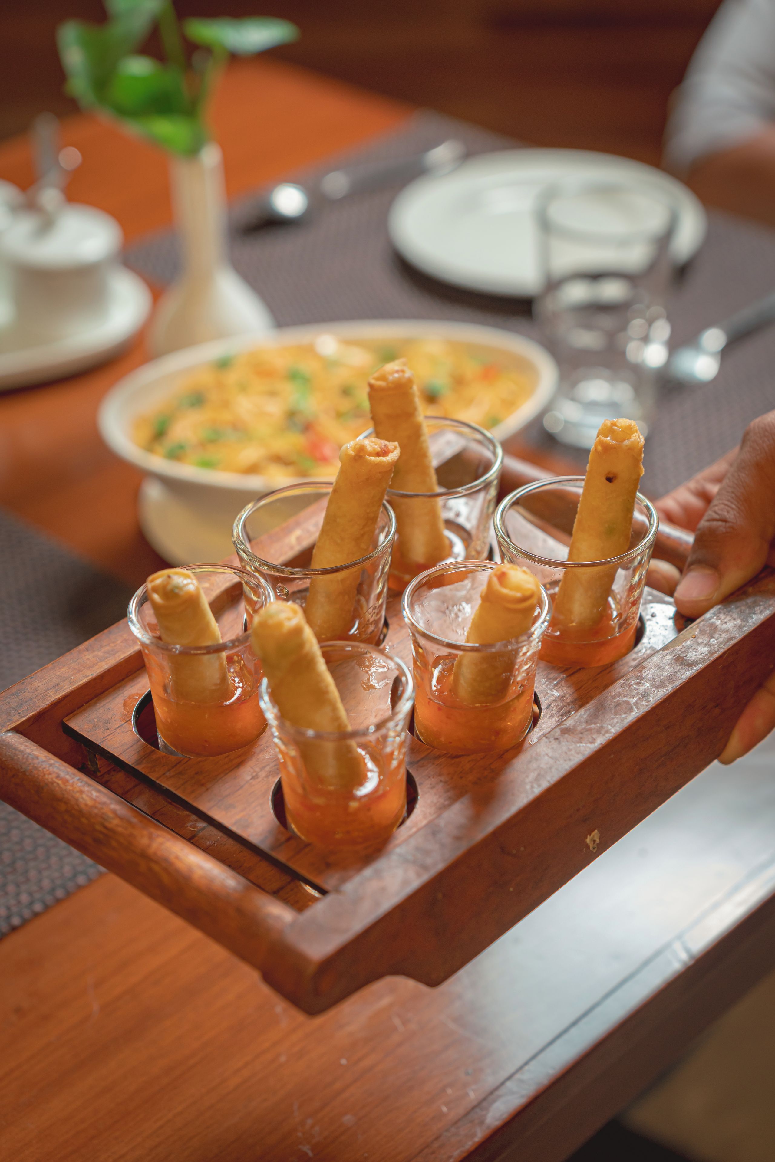 A tray with several glasses containing a golden-brown food item, possibly a dessert or appetizer, on a wooden table.