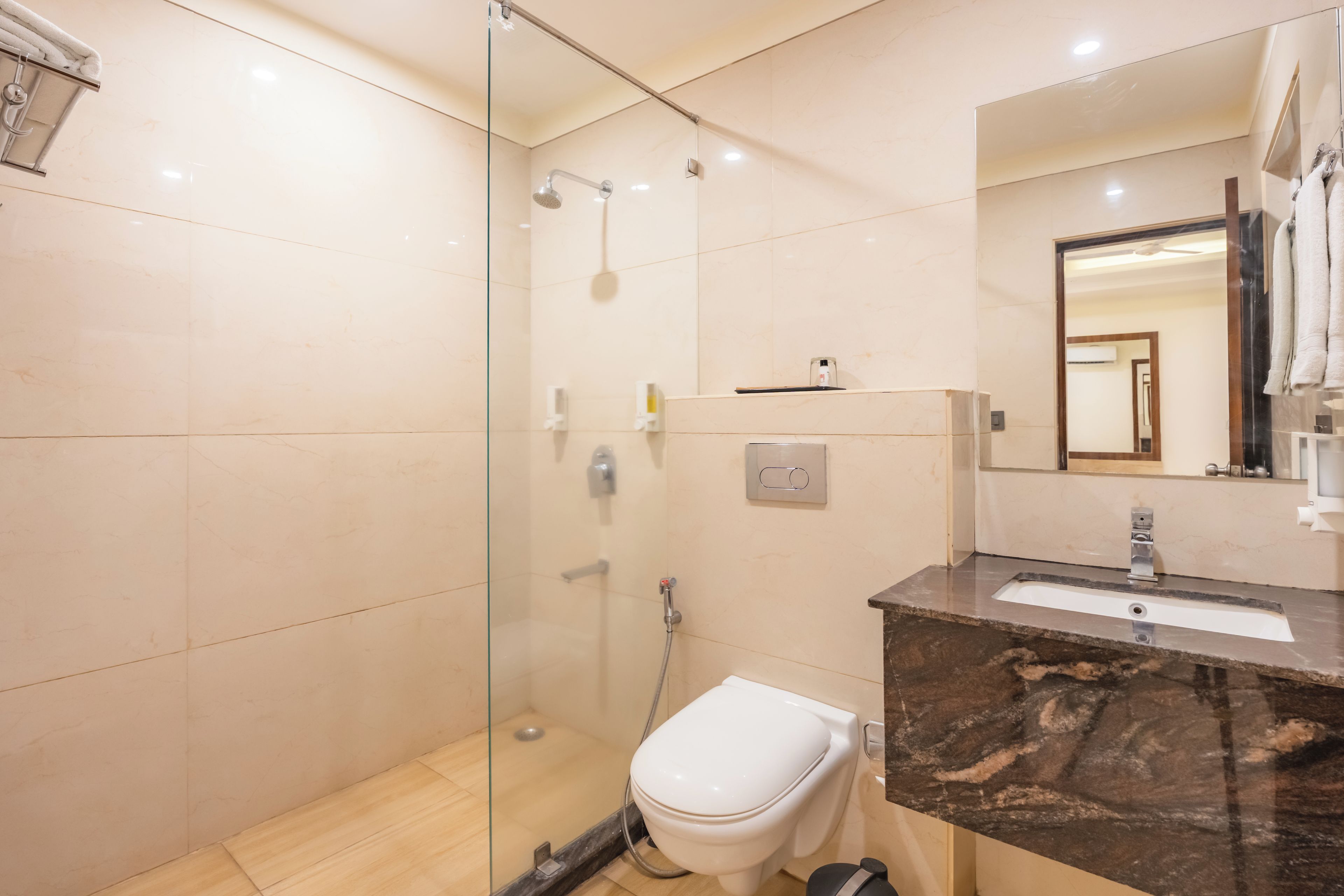 A modern bathroom with a glass-enclosed shower, a white toilet, and a marble countertop with a sink.