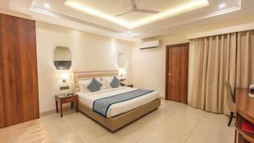 A hotel room with a bed, bedside tables, a ceiling fan, an air conditioning unit, and a door with curtains.