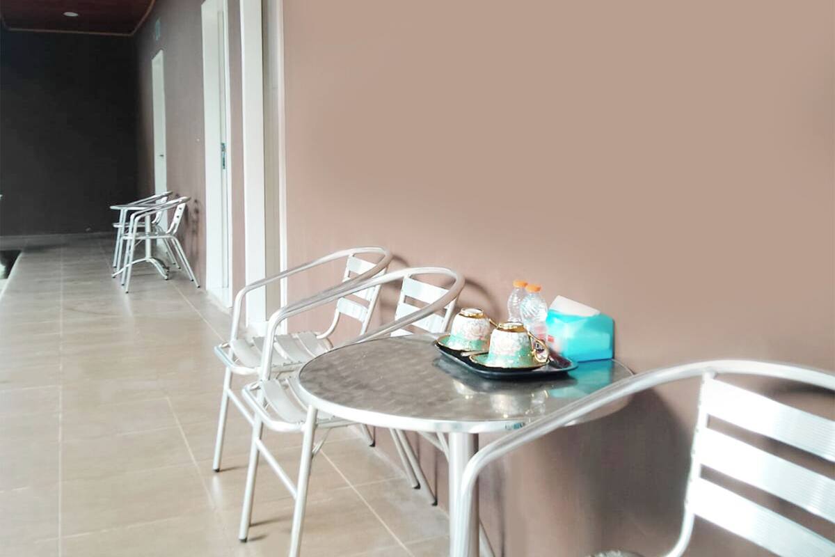 A corridor with a dining area featuring metal chairs and a table with a tray of food and a bottle.