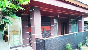 A modern building with a covered entrance, a glass door, and a small outdoor area with potted plants. - Guest House GS Syariah Taman Keluarga (Bekasi)