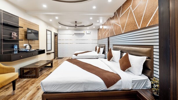 Una habitación de hotel moderna con una cama grande, un escritorio, un televisor y un ventilador de techo.