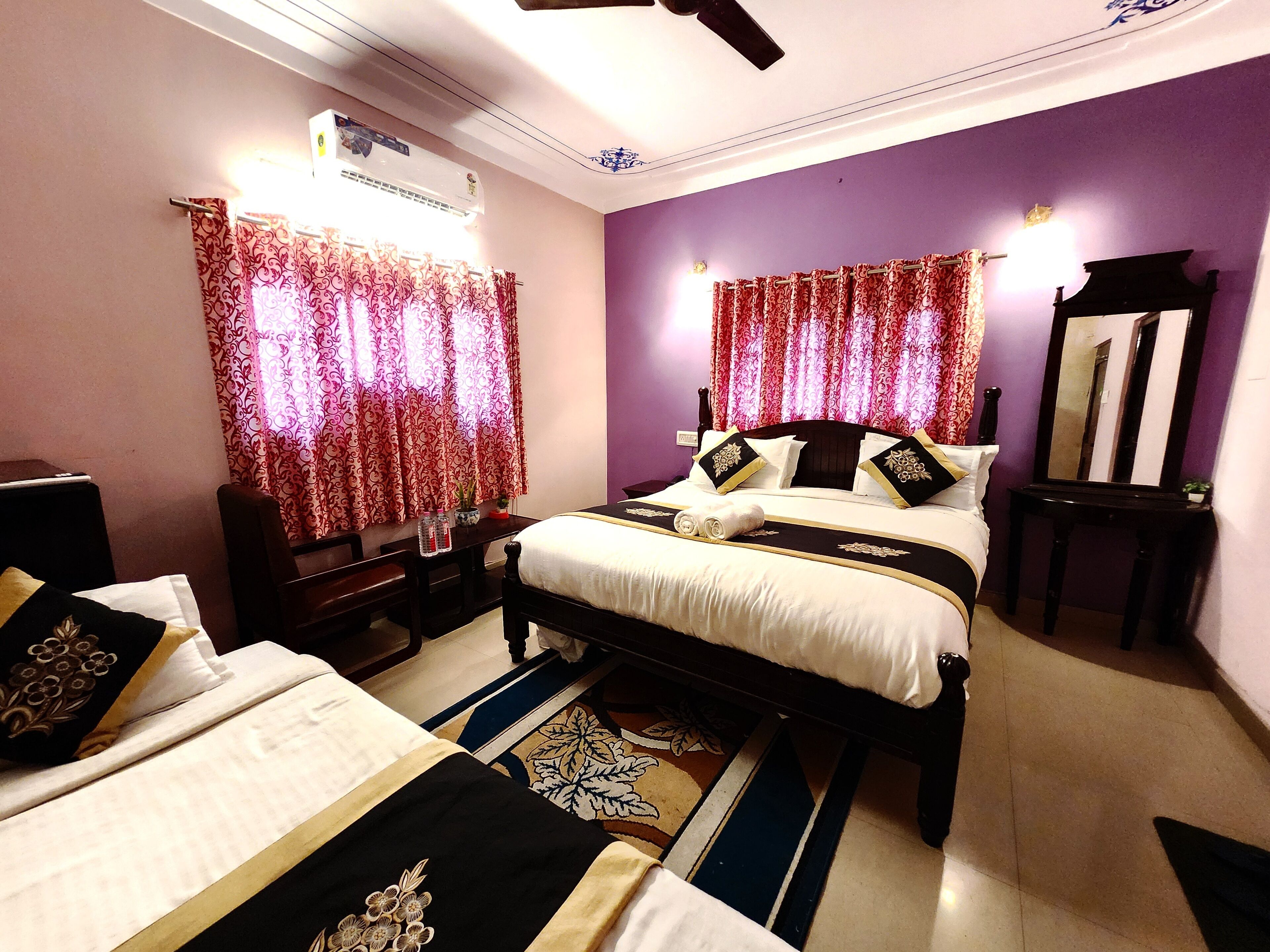A bedroom with two beds, a desk, a chair, a mirror, and an air conditioning unit.