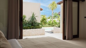 A bedroom with a large bed, a view of a pool, and a stone wall. - Rumah Tiha by Alfred in Bali (Canggu)