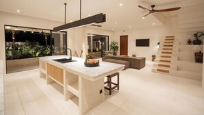 A modern kitchen with a large island, built-in appliances, and a view of a tropical garden. - Rumah Tiha by Alfred in Bali (Canggu)