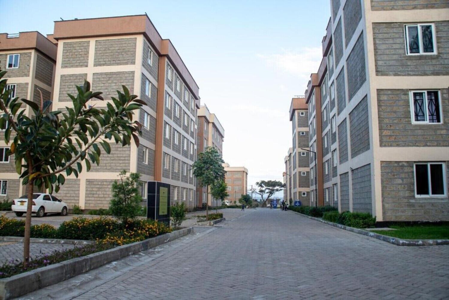 En bostadsbyggnad med en fasad av tegel, många fönster och en kullerstensbelagd gata framför.