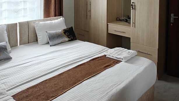 Ein modernes Schlafzimmer mit einem großen Bett, einem Holzschrank und einem Nachttisch.