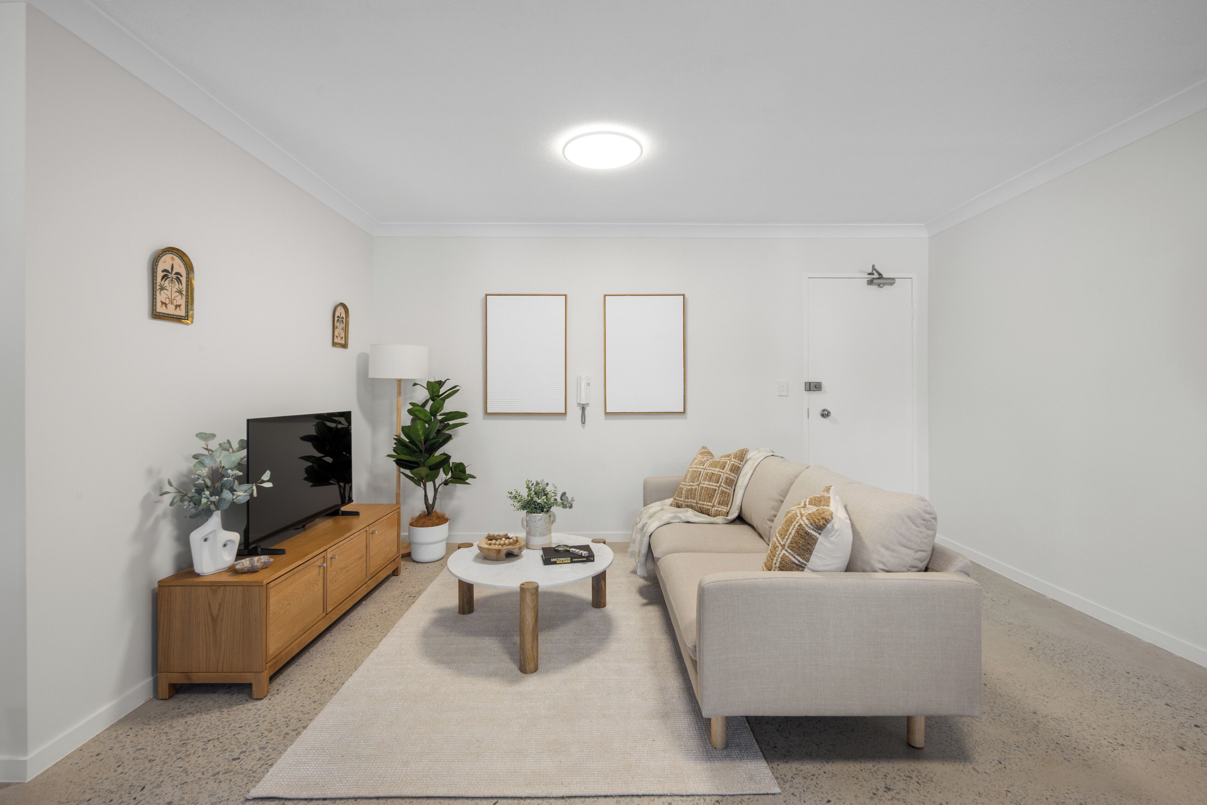 Una sala de estar con sofá, mesa de centro, televisor y objetos decorativos.