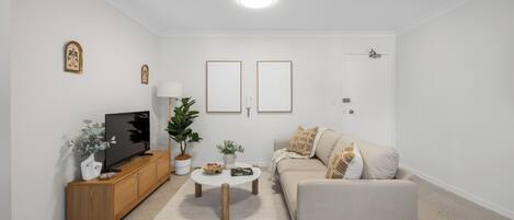 Una sala de estar con sofá, mesa de centro, televisor y objetos decorativos.