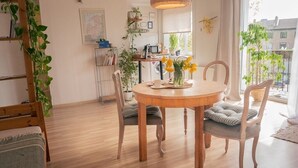A cozy dining area with a wooden table, chairs, and a vase of yellow flowers.