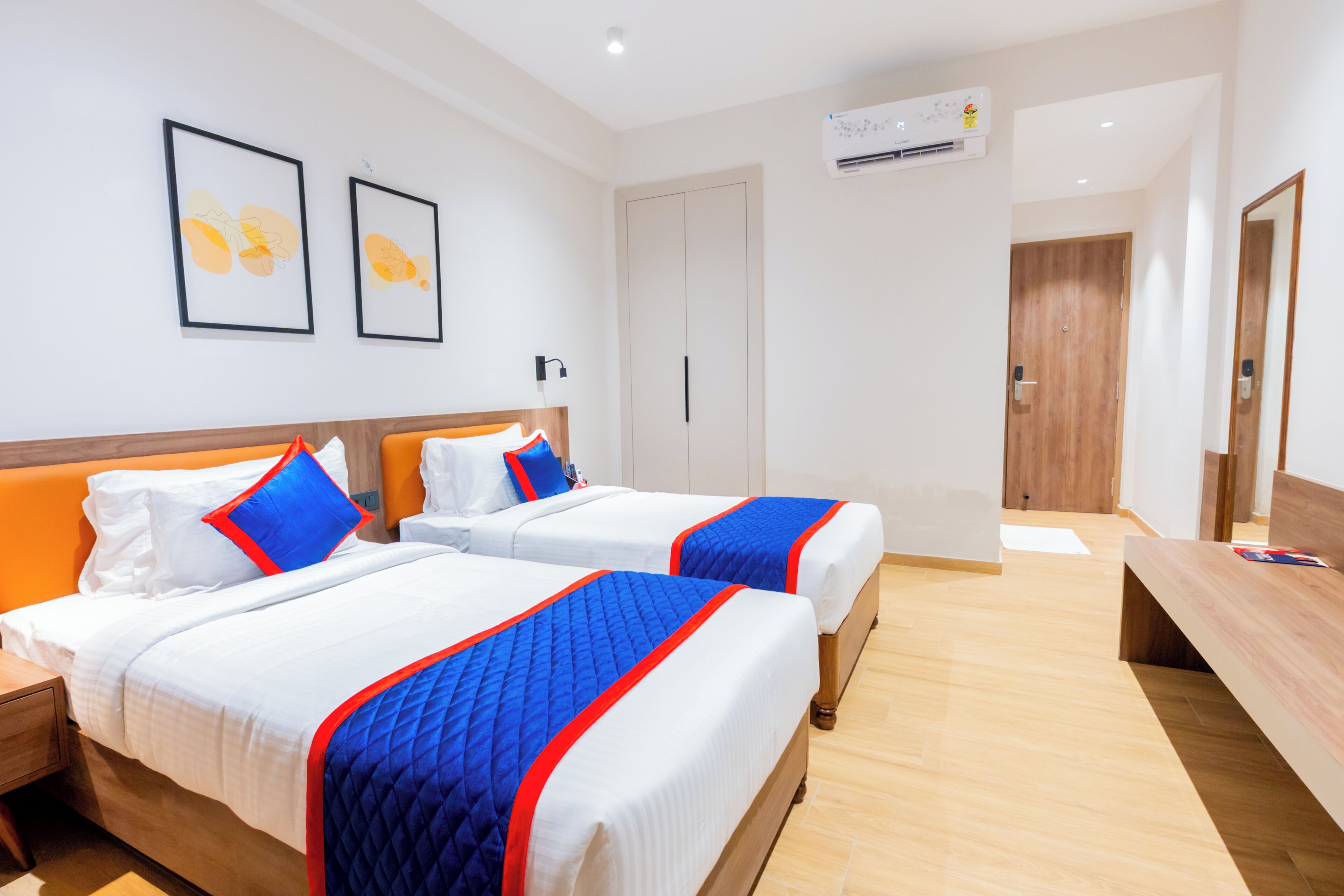 Habitación de hotel con dos camas, un banco de madera, un escritorio y un armario.