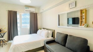 Een hotelkamer met een bed, een bank, een televisie en een raam met gordijnen.