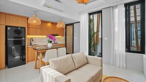 Una cocina moderna con armarios de madera, un refrigerador negro y una zona de comedor con mesa y sillas.