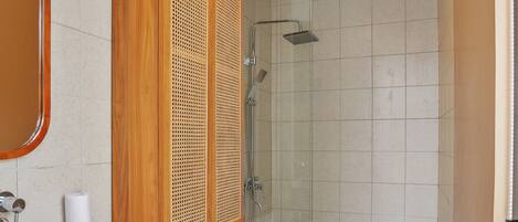A modern bathroom with a wooden vanity, a toilet, and a glass-enclosed shower area.