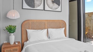 Un dormitorio con cama, mesitas de noche, una planta en maceta y un ventilador de techo.