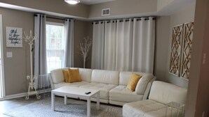 A living room with a white sectional sofa, a coffee table, and a patterned rug.