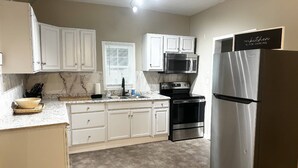 A kitchen with white cabinets, a stainless steel refrigerator, a microwave, and a stove.