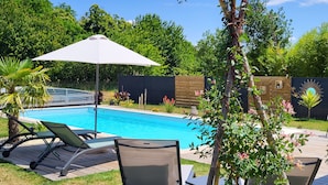 A swimming pool with lounge chairs and an umbrella.