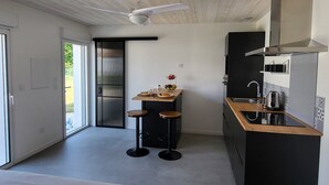 A compact kitchen with a wooden ceiling, a built-in stove, and a small dining area with stools.