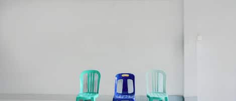 Three plastic chairs against a plain wall with a tiled floor.