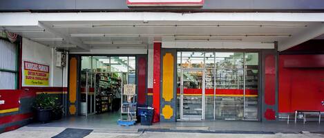 A building with a sign reading "SURYA PASAR SWALAYAN" and a sign for "KUSIUS PARKING" indicating a parking area.