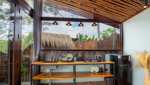 Une cuisine moderne avec un plan de travail en bois, des appareils électroménagers noirs et un toit de chaume visible à travers la fenêtre.