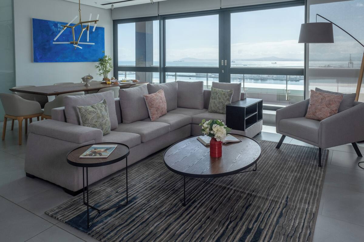 Una sala de estar moderna con un sofá modular, una mesa de centro y un comedor con mesa y sillas.