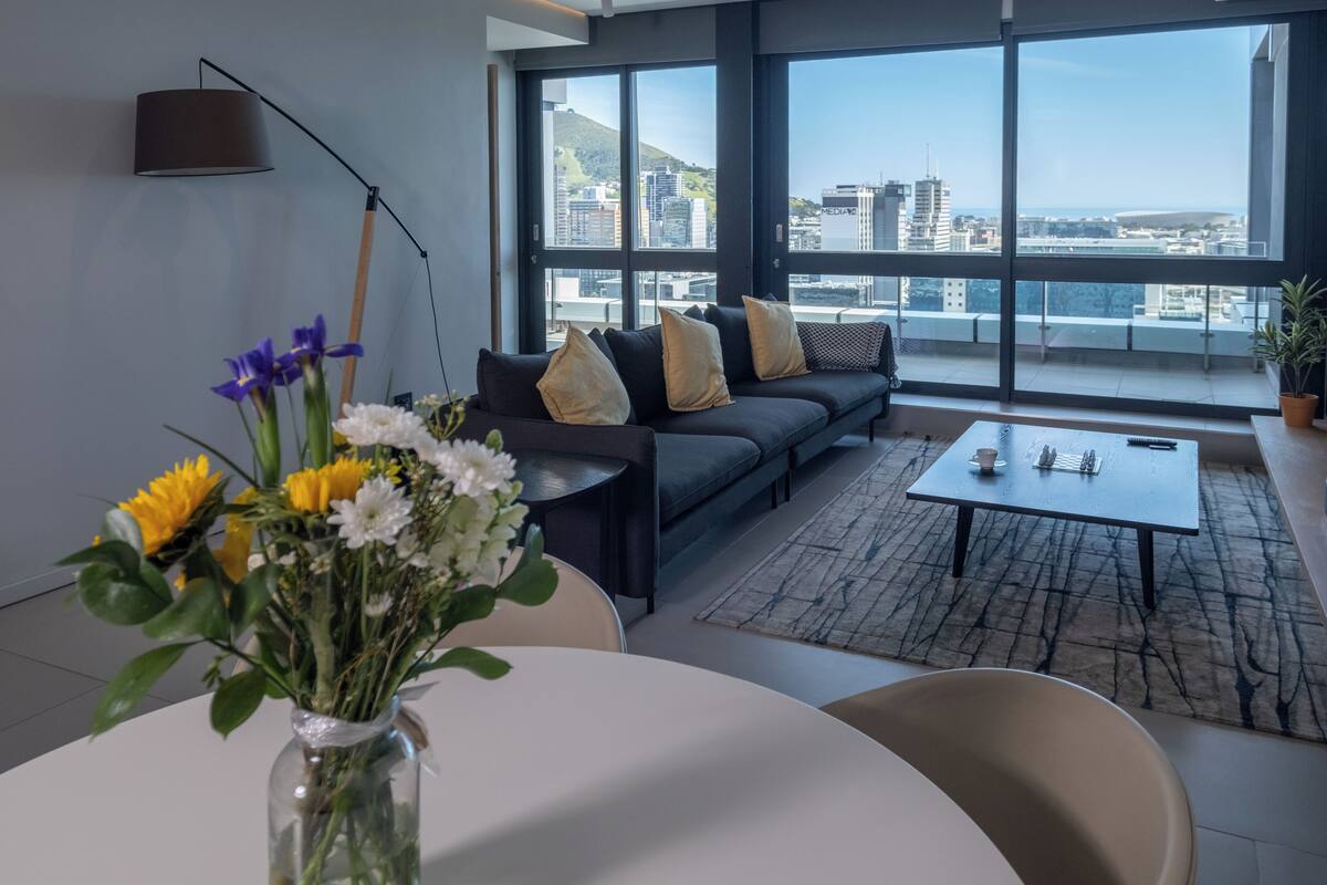 Una sala de estar moderna con un sofá, una mesa de centro y un jarrón de flores.