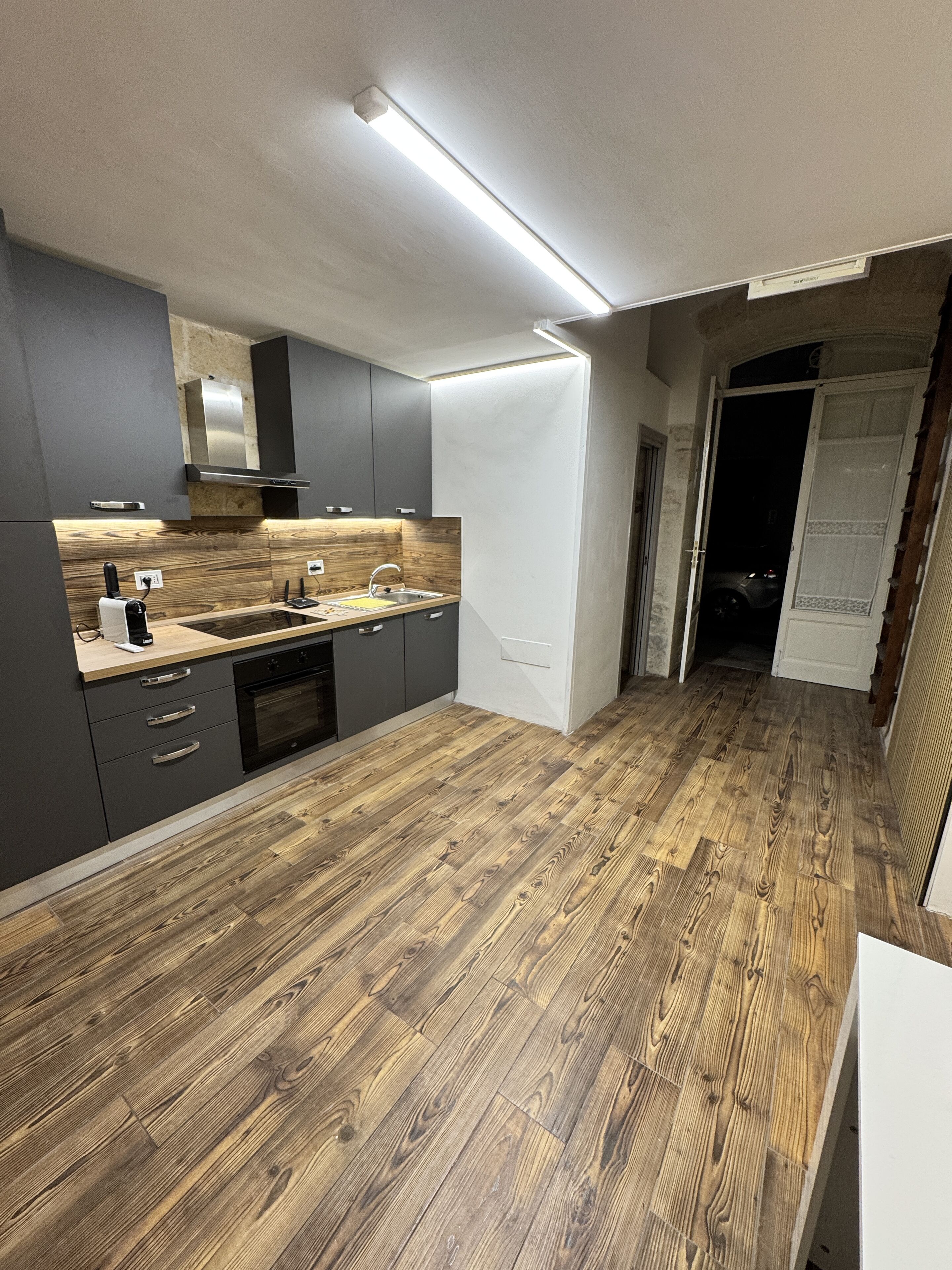 Een moderne keuken met grijze kastjes, een houten aanrechtblad en een inbouwoven.