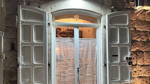 Una doppia porta con un pannello di vetro satinato al centro, incastonata in un muro di pietra con una piccola finestra sopra.
