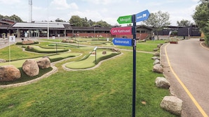 A miniature golf course with directional signs for 'Minigolf', 'Café Kyshuset', and 'Badeanstalt'. - 6 Person Holiday Park Home in Gilleleje (Gilleleje)