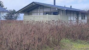A modern house with a sloped roof, large windows, and a wooden fence in front. - 6 Person Holiday Park Home in Gilleleje (Gilleleje)