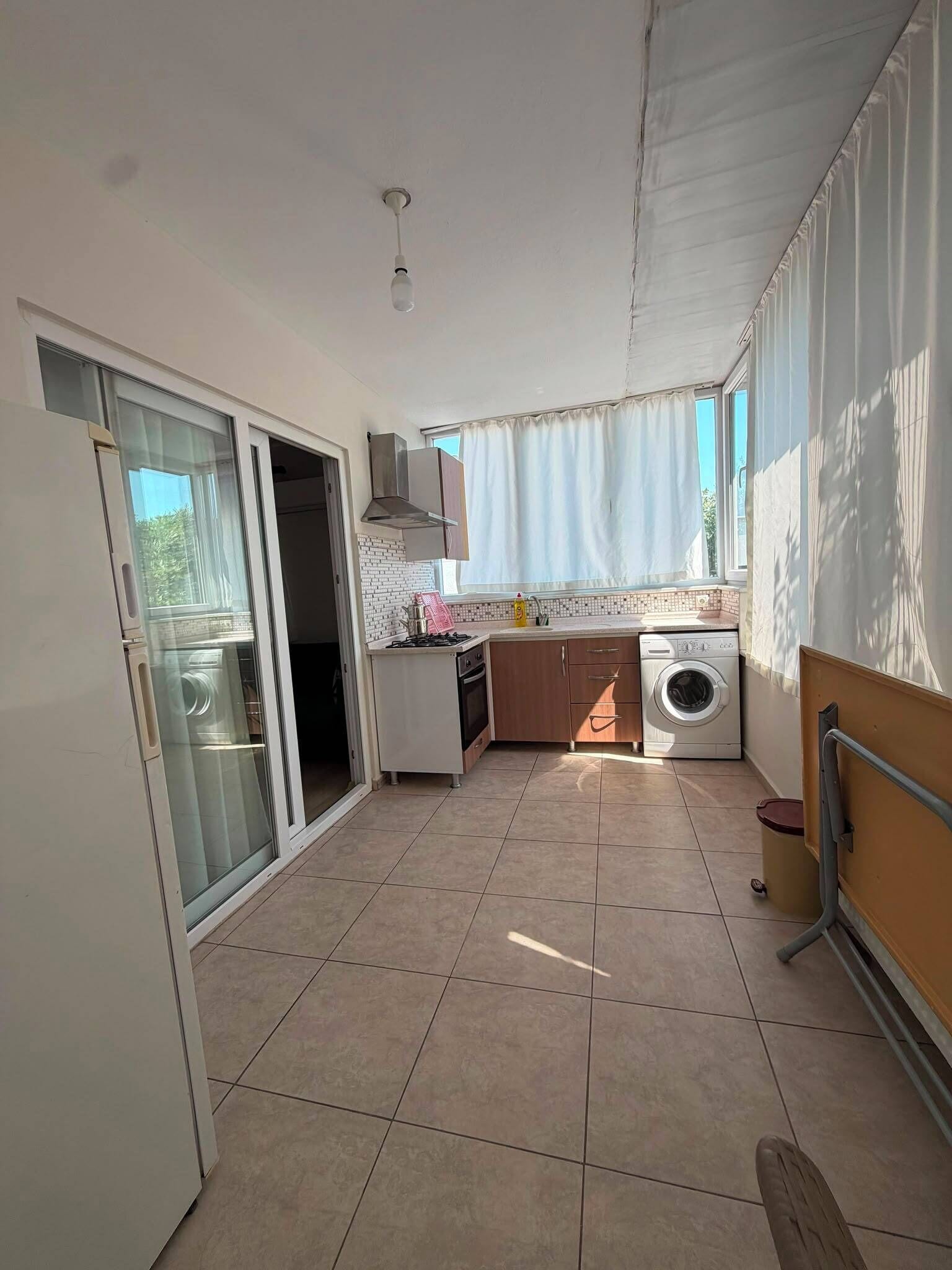 A compact kitchen with a washing machine, a stove, and a sink.