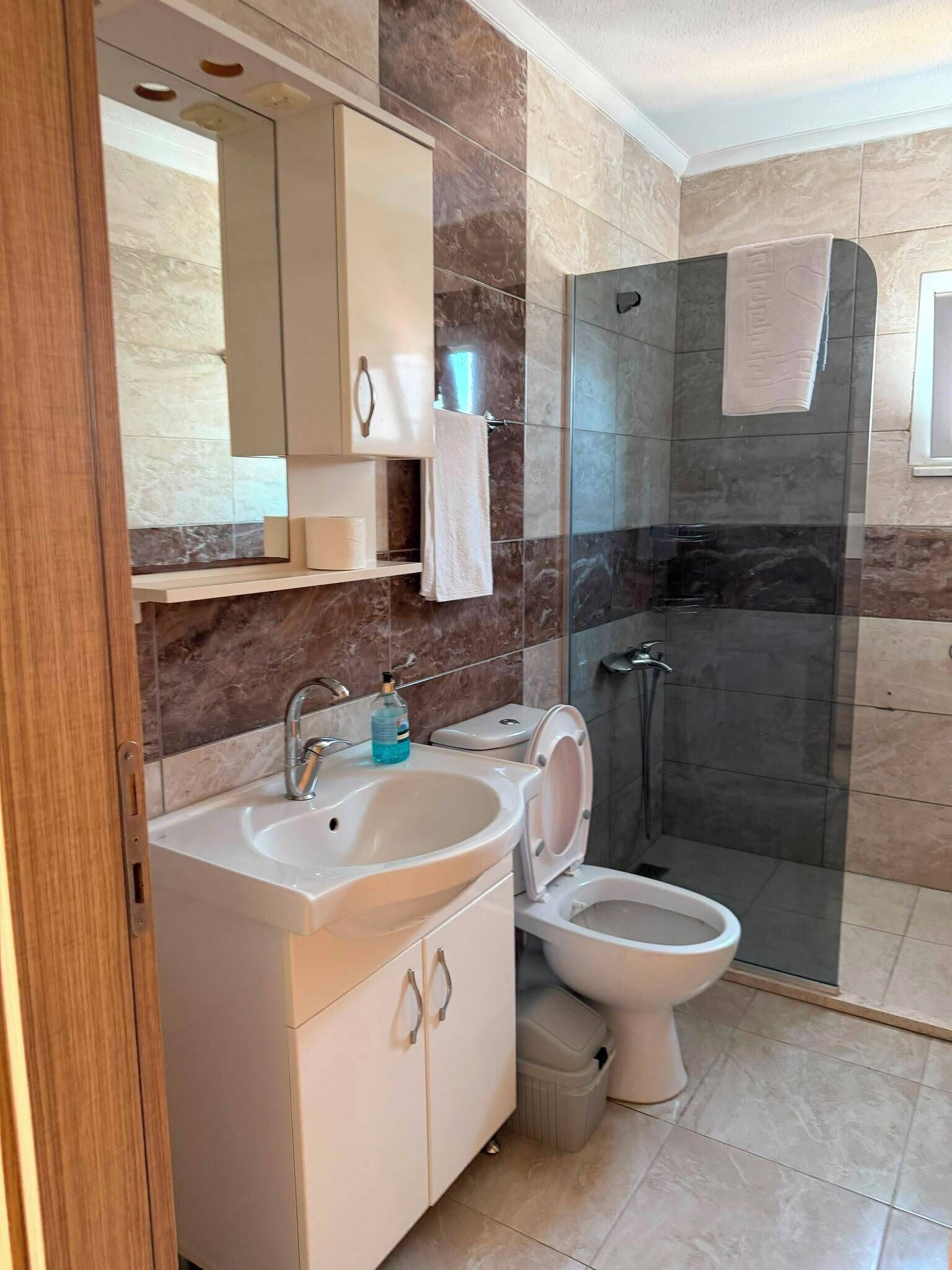 Une salle de bain moderne avec une douche à parois de verre, des toilettes et un lavabo avec un miroir au-dessus.