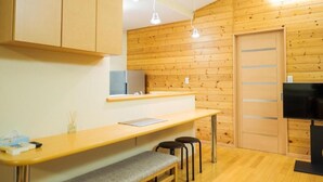 A modern kitchen with wooden walls, a wooden countertop, a bench, two stools, and a TV. - Yunosato699-89 (Rankoshi)
