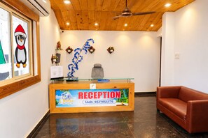 Un mostrador de recepción con cubierta de vidrio, un sofá de cuero marrón y un ventilador de techo.