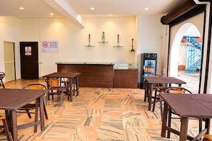 A restaurant interior with a marble floor, wooden tables and chairs, a counter with a cash register, and a sign prohibiting smoking outdoors. - Omnia Beach Resort Near Candolim Beach (Candolim)