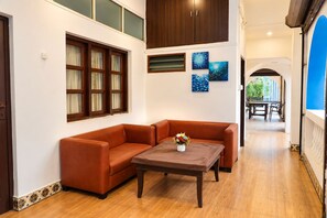 A room with a brown leather sofa, a wooden coffee table, and a painting on the wall. - Omnia Beach Resort Near Candolim Beach (Candolim)