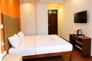 Habitación de hotel con cama, escritorio con televisor de pantalla plana, puerta de madera y luz instalada en la pared.