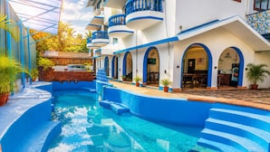 Una piscina con escalones azules y un edificio con balcones.