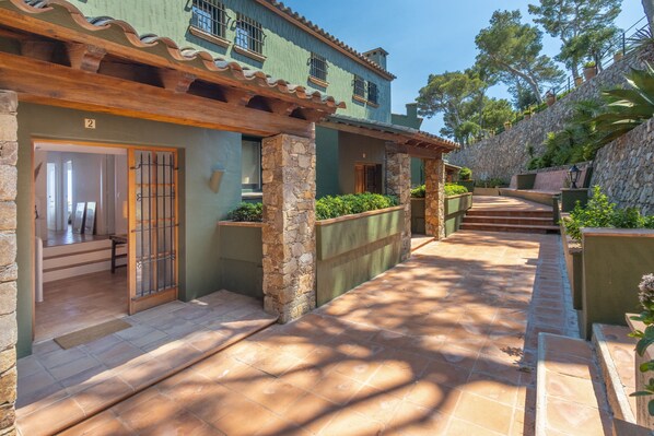 A courtyard with stone pillars, a wooden pergola, and a stone wall.