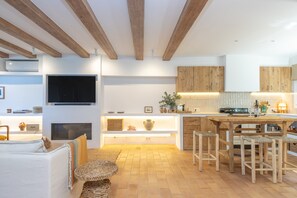A modern kitchen with wooden beams, a TV, and bar stools.
