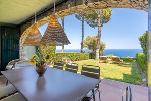 A patio with a table, chairs, and hanging lamps overlooking a scenic view.