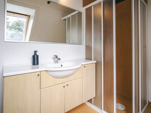 A bathroom with a white sink, a mirror above it, and a shower with frosted glass doors.