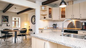 Una cocina con encimeras de granito, electrodomésticos de acero inoxidable, armarios de madera y un comedor con mesa y sillas.