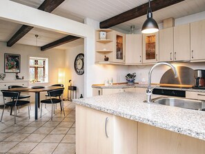 A kitchen with granite countertops, stainless steel appliances, wooden cabinets, and a dining area with a table and chairs.