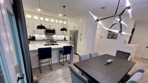 A modern kitchen with white cabinets, a central island, and pendant lighting.