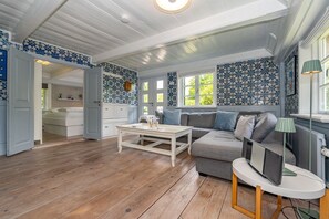 Un vaste espace de vie doté d’un plancher en bois, d’un canapé gris, d’une table basse blanche et d’un téléviseur posé sur un meuble.