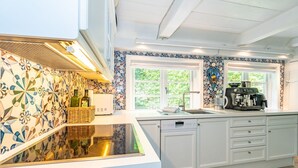 A modern kitchen with a large island, white cabinetry, and patterned backsplash. - Kapitänshuis - Captain's house on Sylt with garden, terrace and comfortable (Sylt)